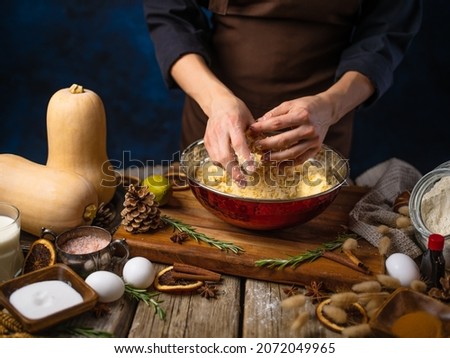 The chef kneads the dough for a traditional American pumpkin pie. Lots of ingredients and decor on a rough wooden table. Thanksgiving, Halloween. New Year, Christmas, family holidays.
