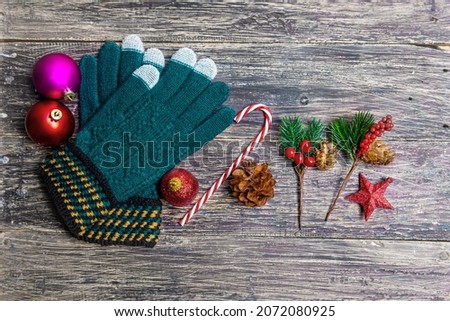 Pine Cone with a winter glove and colorful Christmas ball on wooden background. Christmas decoration