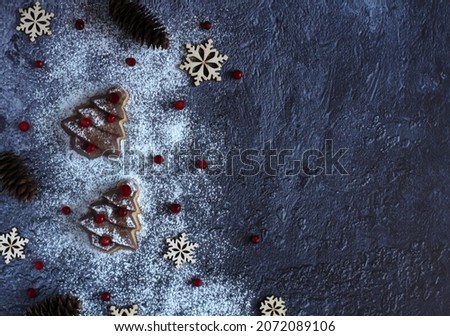 Christmas tree cake with berries, snowflakes and powdered sugar on a dark background