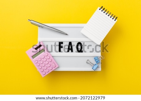 FAQ word on lightbox with calculator and office supplies on yellow background, top view
