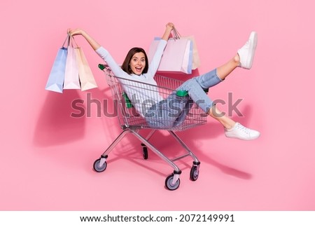 Photo of cute excited young woman wear white sweater sitting shopping cart holding bargains smiling isolated pink color background Royalty-Free Stock Photo #2072149991