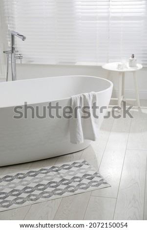 Stylish mat on floor near tub in bathroom. Interior design