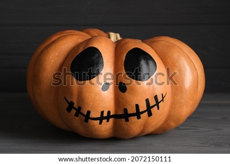 Pumpkin with drawn spooky face on grey table. Halloween celebration