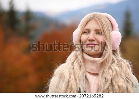 Young beautiful woman wearing warm earmuffs in mountains Royalty-Free Stock Photo #2072165282