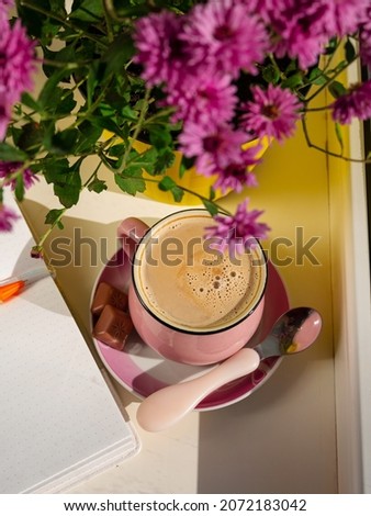 Coffee cup chocolate notebook beautiful pink autumn Chrysanthemum flowers in yellow pot on window. Cozy home vibes fall mood Urban spaces plants Drinking hot cocoa in cold weather Good morning concept