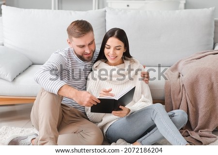 Young couple reading book at home