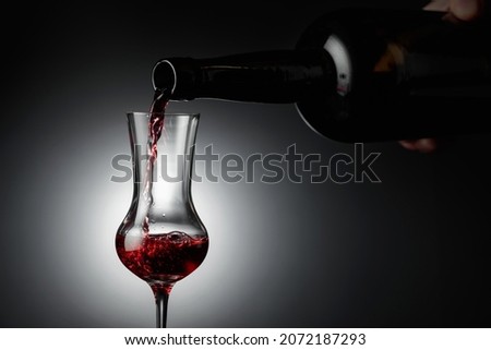 Dessert wine or liqueur is poured into a glass from an ancient bottle. Copy space. Royalty-Free Stock Photo #2072187293