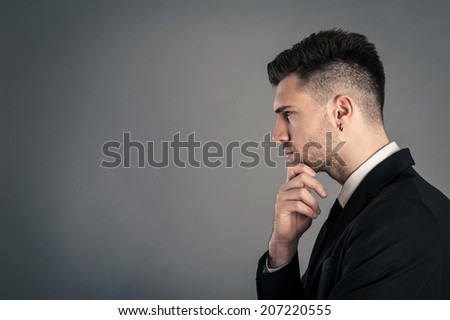 Young businessman portrait thinking against dark background. Conceptual image. 