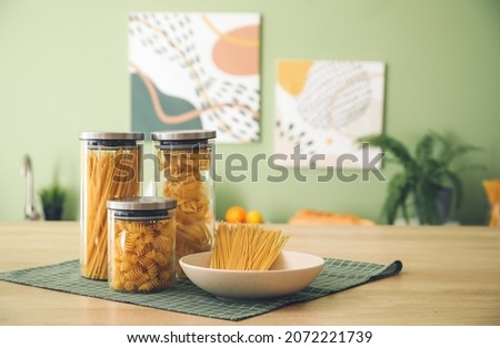 Jars and plate with uncooked pasta on kitchen counter