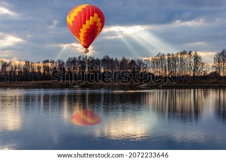 A bright hot air balloon flies over the lake during sunset. Makarov Ukraine