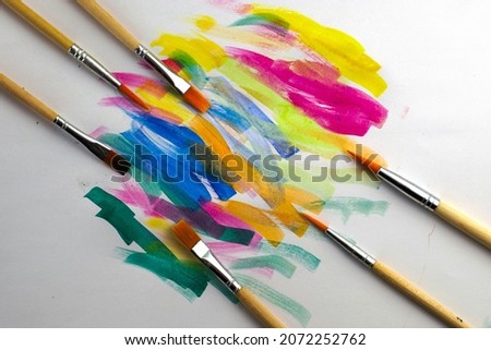 brushes for drawing folded diagonally on a white sheet with samples of paints. High quality photo