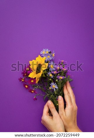Autumn flower arrangement purple background female hands. Bouquet of colorful autumn flowers. Creative vertical greeting card. The layout for the design of greetings, the concept of the Mother's Day