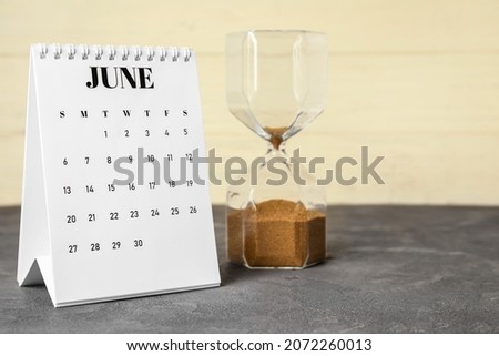 Flip paper calendar with hourglass on table