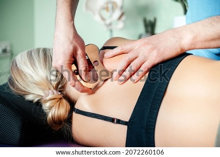 IASTM mysofacial Release For Rhomboid And Back Pain Using Smart Tools, Therapist using IASTM instrument to treat scapular pain Royalty-Free Stock Photo #2072260106