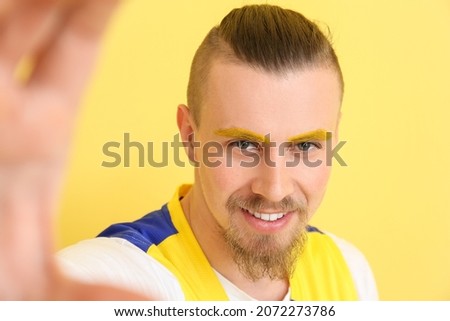 Stylish young man taking selfie on yellow background