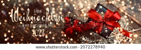 Christmas greeting card with text in German -  Frohe Weihnachten means Merry Christmas and Happy New Year 2022 - Gift box with red bow