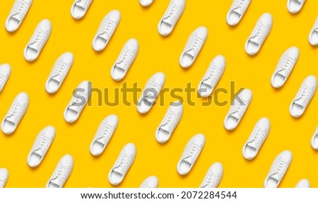 White women's leather sneakers on yellow background flat lay pattern. Stylish youth sneakers, sports shoes, genuine leather footwear. Minimalistic shoe store advertising fashion style Shoe background Royalty-Free Stock Photo #2072284544