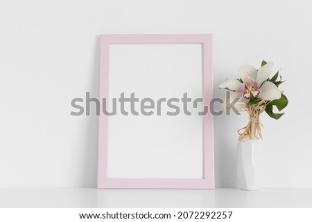 Pink frame mockup with a orchid on the white table.