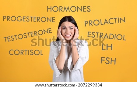 Hormones imbalance. Stressed young woman and different words on yellow background Royalty-Free Stock Photo #2072299334
