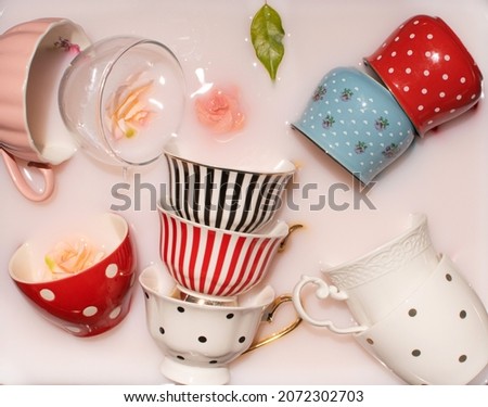 Cute patterns, polka dot, stripes, floral tea and coffe cups soaked in milk. Creative composition, after party theme, domestic chores, every day routine.