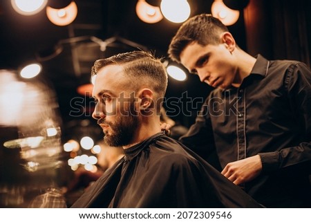 Young man at barbershop trimming hair Royalty-Free Stock Photo #2072309546