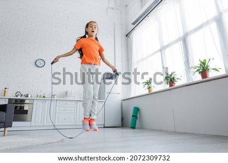 Low angle view of kid jumping with skipping rope in kitchen Royalty-Free Stock Photo #2072309732