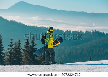 man walking by hill with snowboard mountains on background