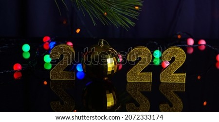                    The new 2022 year, golden numbers and lights are reflected in the mirror, on a black background            