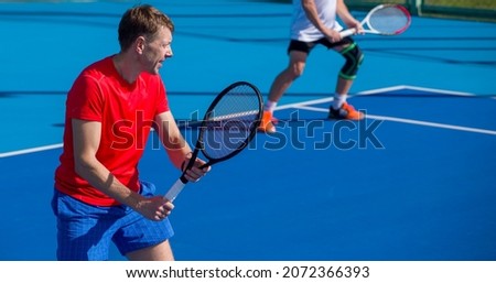 Tennis player playing tennis on a hard court on a bright sunny day Royalty-Free Stock Photo #2072366393