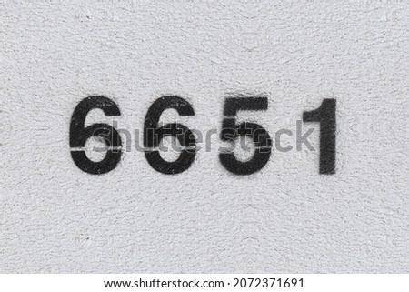 Black Number 6651 on the white wall. Spray paint. Number six thousand six hundred and fifty one.