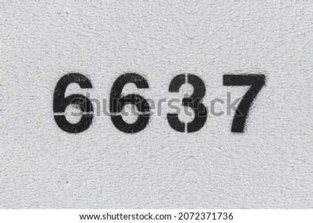Black Number 6637 on the white wall. Spray paint. Number six thousand six hundred thirty seven.