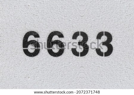 Black Number 6633 on the white wall. Spray paint. Number six thousand six hundred thirty three.