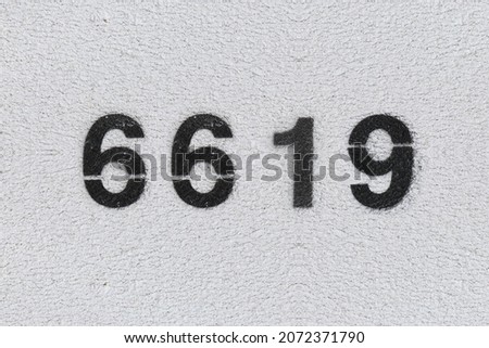 Black Number 6619 on the white wall. Spray paint. Number six thousand six hundred nineteen.