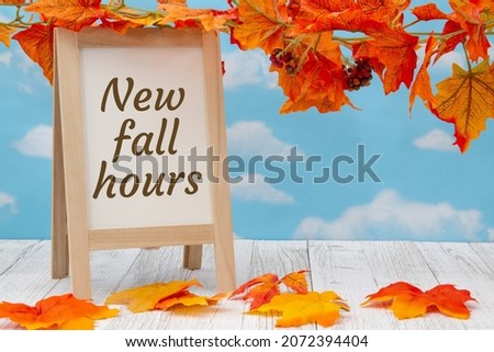 New fall hours sign with standing whiteboard on weathered wood with fall leaves