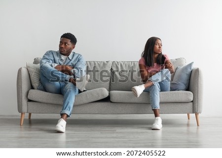 Family Conflict Concept. Stubborn black couple sit on couch back to back avoid talking after fight, offended man and woman separated on sofa ignoring one another, husband and wife not looking in eyes Royalty-Free Stock Photo #2072405522