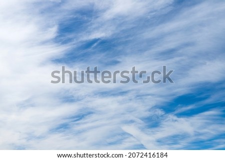 White cirrostratus clouds in blue sky on a daytime, natural photo background