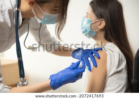 Protect. Close up doctor or nurse giving vaccine to patient using the syringe injected. Works in face mask. Protection against coronavirus, COVID-19 pandemic and pneumonia. Healthcare, medicine.