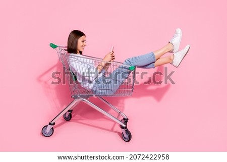 Photo of shiny cute young woman wear white sweater sitting shopping cart chatting modern gadget smiling isolated pink color background Royalty-Free Stock Photo #2072422958