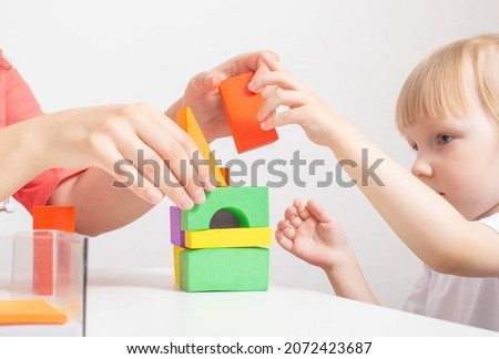 Woman doctor pediatrician plays colorful cubes with a 3-4 girl. Children's health, background