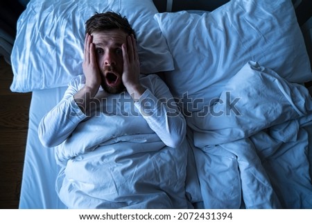 Man had a terrible nightmare, he woke up in horror, looking frightened with big eyes at the camera. Insomnia and mental health concept. Royalty-Free Stock Photo #2072431394
