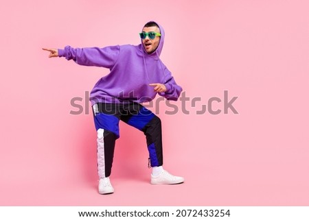Full body photo of cute young brunet guy dance point wear eyewear hoodie pants shoes isolated on pink background Royalty-Free Stock Photo #2072433254