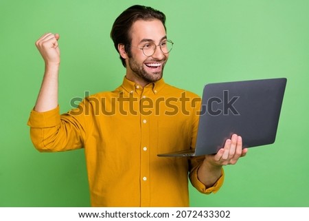 Photo of hooray young hr brunet guy hand fist look laptop wear eyewear yelllow shirt isolated on green color background