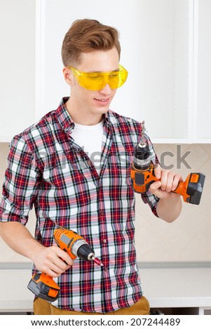 young worker chooses between a drill and screwdriver