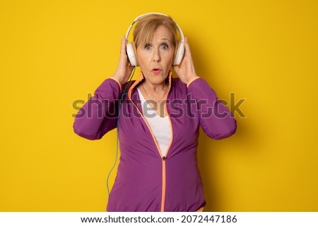 Smiling Sport Mature sport woman in headphones isolated on yellow background. Active senior lifestyle