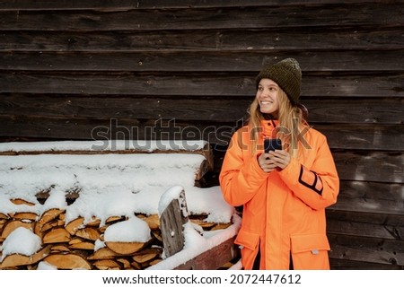 Beautiful girl smiling snowboarder standing alone with phone in hands. Mountain outdoor, winter sport activity.