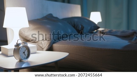 Modern bedroom interior at night time with design furnishing and alarm clock Royalty-Free Stock Photo #2072455664