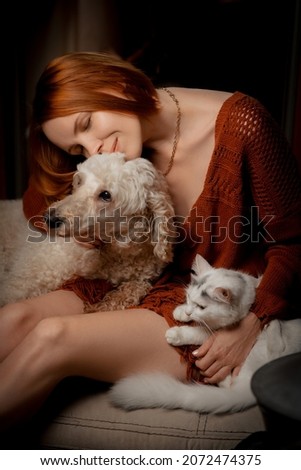 Attractive forty year old woman with a white cat and dog. Pets care concept.