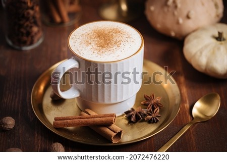 Cup of pumpkin spice late with cinnamon sticks, pumpkins star anise and nutmeg in a rustic moody and vintage atmosphere Royalty-Free Stock Photo #2072476220