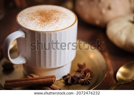 Cup of pumpkin spice late with cinnamon sticks, pumpkins star anise and nutmeg in a rustic moody and vintage atmosphere