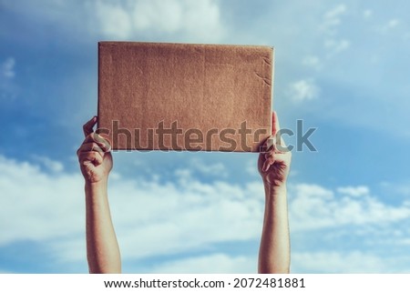 Man holding blank piece of cardboard against blue sky Royalty-Free Stock Photo #2072481881